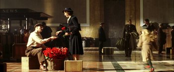 Movie still from “Pearl Harbor” (2001), directed by Michael Bay – A woman holding a red rose standing next to luggage; Wide shot, High angle