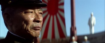 Movie still from “Pearl Harbor” (2001), directed by Michael Bay – An older man wearing a hat in front of a red and white flag; Close Up shot, Low angle