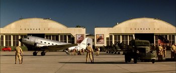 Movie still from “Pearl Harbor” (2001), directed by Michael Bay – A man standing in front of a building with planes on the ground; Extreme Wide shot, Low angle