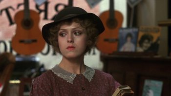 Movie still from “Pennies from Heaven” (1981), directed by Herbert Ross – A woman in a hat holding a book in a room; Close Up shot, Over the shoulder angle
