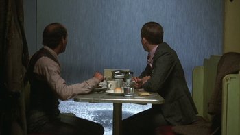 Movie still from “Pennies from Heaven” (1981), directed by Herbert Ross – Two men sitting at a table in front of water; Wide shot, Over the shoulder angle