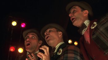 Movie still from “Pennies from Heaven” (1981), directed by Herbert Ross – A group of three men singing in front of a crowd of onlookers; Close Up shot, Low angle