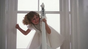 Movie still from “Pennies from Heaven” (1981), directed by Herbert Ross – A young girl holding onto a large white upright bass; Medium shot, Low angle