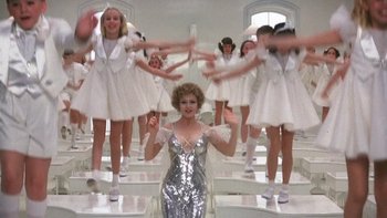 Movie still from “Pennies from Heaven” (1981), directed by Herbert Ross – A group of women in white dresses and a woman in a silver dress; Wide shot, Low angle