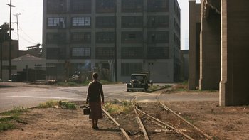 Movie still from “Pennies from Heaven” (1981), directed by Herbert Ross – A woman walking down the street with a suitcase; Extreme Wide shot, High angle