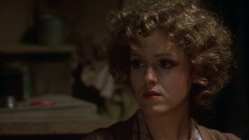 Movie still from “Pennies from Heaven” (1981), directed by Herbert Ross – A woman with curly brown hair sitting in a dark room; Close Up shot, Over the shoulder angle