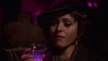 Movie still from “Pennies from Heaven” (1981), directed by Herbert Ross – A woman holding a glass of water and wearing a purple hat; Close Up shot, Low angle