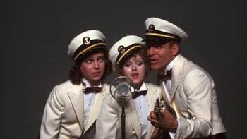 A group of three people in white suits and hats singing
