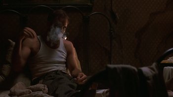 Movie still from “Pennies from Heaven” (1981), directed by Herbert Ross – A man sitting on a bed smoking a cigarette; Medium shot, Low angle