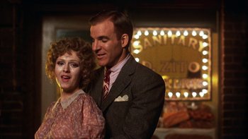 Movie still from “Pennies from Heaven” (1981), directed by Herbert Ross – A man and a woman standing next to each other in front of lights; Close Up shot, Over the shoulder angle