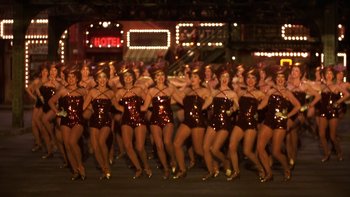 Movie still from “Pennies from Heaven” (1981), directed by Herbert Ross – A group of women dressed in red are dancing in the street; Wide shot, High angle
