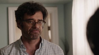 Movie still from “People Places Things” (2015), directed by Jim Strouse – A person wearing glasses and a plaid shirt; Close Up shot, Over the shoulder angle