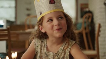 Movie still from “People Places Things” (2015), directed by Jim Strouse – A little girl wearing a paper hat with bananas on top of her head; Close Up shot, Over the shoulder angle