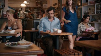Movie still from “People Places Things” (2015), directed by Jim Strouse – A man sitting at a table in a restaurant with a tray of food on his lap; Medium shot, Over the shoulder angle