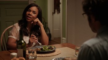 Movie still from “People Places Things” (2015), directed by Jim Strouse – A woman sitting at a table with a plate of food; Medium shot, Over the shoulder angle
