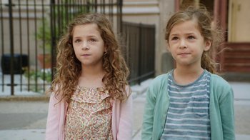 Movie still from “People Places Things” (2015), directed by Jim Strouse – Two little girls standing next to each other on the sidewalk; Close Up shot, High angle