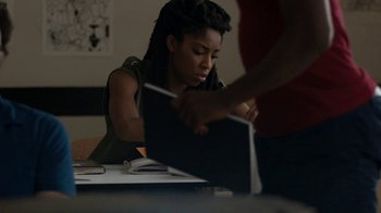 Movie still from “People Places Things” (2015), directed by Jim Strouse – A woman sitting at a table looking at a laptop computer; Medium shot, Over the shoulder angle