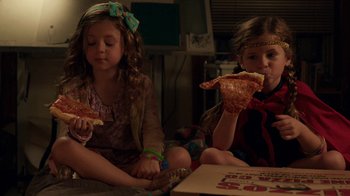 Movie still from “People Places Things” (2015), directed by Jim Strouse – Two little girls sitting next to each other eating pizza; Medium shot, High angle