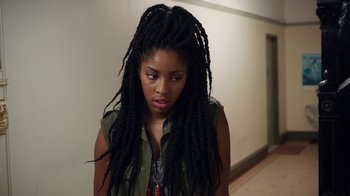 Movie still from “People Places Things” (2015), directed by Jim Strouse – A woman with long dreadlocks standing next to a wall; Close Up shot, Over the shoulder angle