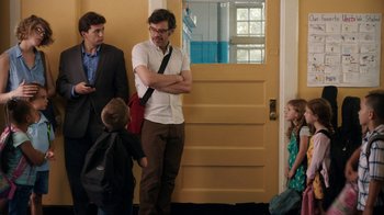 Movie still from “People Places Things” (2015), directed by Jim Strouse – A group of men standing next to each other in front of a yellow door; Medium shot, Over the shoulder angle