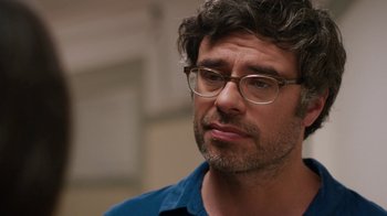 Movie still from “People Places Things” (2015), directed by Jim Strouse – A person wearing glasses and a blue shirt; Close Up shot, Over the shoulder angle