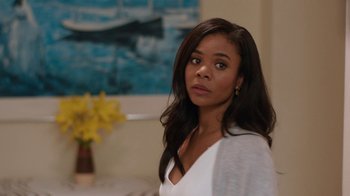 Movie still from “People Places Things” (2015), directed by Jim Strouse – A woman in a white shirt is standing in a room; Medium shot, Over the shoulder angle