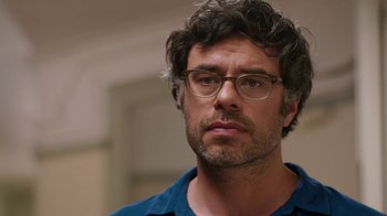 Movie still from “People Places Things” (2015), directed by Jim Strouse – A person wearing glasses and a blue shirt; Close Up shot, Over the shoulder angle