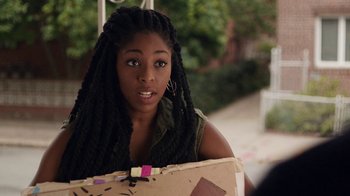 Movie still from “People Places Things” (2015), directed by Jim Strouse – A young woman with long dreadlocks holding a piece of paper; Close Up shot, Over the shoulder angle