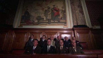 Movie still from “Performance” (1970), directed by Donald Cammell – A group of men sitting in front of a painting; Wide shot, Low angle