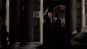 Movie still from “Performance” (1970), directed by Donald Cammell – An older man in a suit and tie holding a knife; Medium shot, Low angle