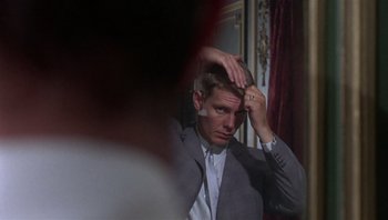 Movie still from “Performance” (1970), directed by Donald Cammell – A man in a gray suit is combing his hair; Close Up shot, Over the shoulder angle