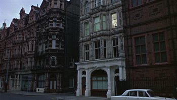 Movie still from “Performance” (1970), directed by Donald Cammell – An old fire station in the middle of a city; Extreme Wide shot, Low angle