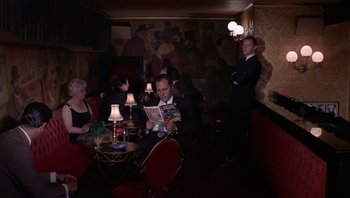 Movie still from “Performance” (1970), directed by Donald Cammell – A group of people sitting at a table in a room; Wide shot, High angle