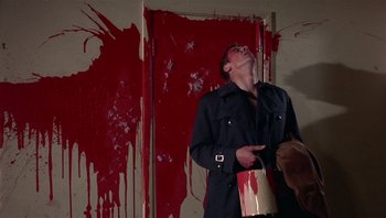 Movie still from “Performance” (1970), directed by Donald Cammell – A man holding a paint bucket in front of a wall; Medium shot, Low angle