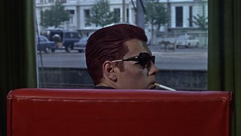 Movie still from “Performance” (1970), directed by Donald Cammell – A man in sunglasses smoking a cigarette while sitting in a car; Close Up shot, Low angle