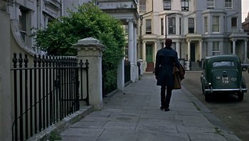 Movie still from “Performance” (1970), directed by Donald Cammell – A woman walking down a sidewalk holding a bag; Extreme Wide shot, Low angle