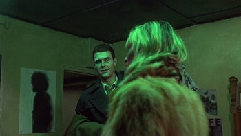 Movie still from “Performance” (1970), directed by Donald Cammell – A man and a woman are standing in front of a mirror; Medium shot, Over the shoulder angle