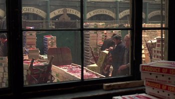 Movie still from “Performance” (1970), directed by Donald Cammell – A group of people standing in a room with boxes; Wide shot, High angle