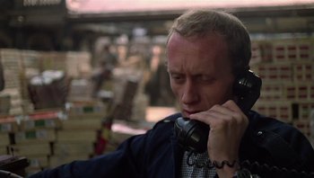 Movie still from “Performance” (1970), directed by Donald Cammell – A man talking on a phone while sitting down; Close Up shot, Low angle