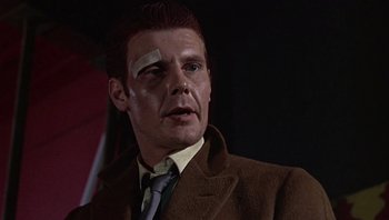 Movie still from “Performance” (1970), directed by Donald Cammell – A person wearing a suit and tie; Close Up shot, Low angle