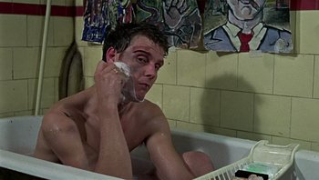 Movie still from “Performance” (1970), directed by Donald Cammell – A man sitting in a bath tub while talking on the phone; Close Up shot, Low angle