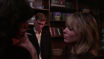 Movie still from “Performance” (1970), directed by Donald Cammell – A man and two women are standing in a room; Medium shot, Over the shoulder angle
