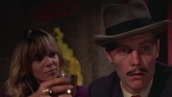 Movie still from “Performance” (1970), directed by Donald Cammell – A man and a woman sitting next to each other holding a drink; Close Up shot, Low angle