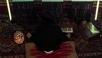 Movie still from “Performance” (1970), directed by Donald Cammell – A person sitting on a bed with a keyboard; Medium shot, Overhead angle