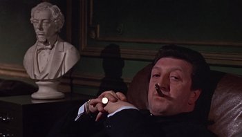 Movie still from “Performance” (1970), directed by Donald Cammell – A man smoking a cigarette while sitting in a chair; Close Up shot, Low angle
