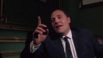 Movie still from “Performance” (1970), directed by Donald Cammell – A man wearing a suit and tie pointing to the sky; Close Up shot, Low angle