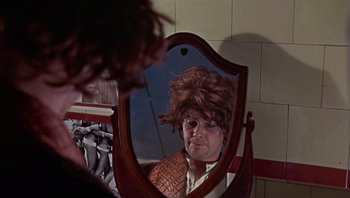 Movie still from “Performance” (1970), directed by Donald Cammell – A man with a wig looking in a mirror; Close Up shot, Over the shoulder angle