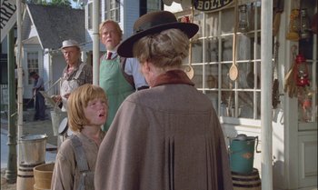 Movie still from “Pete's Dragon” (1977), directed by Don Chaffey – A group of people standing in front of a building; Medium shot, Over the shoulder angle