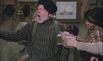 Movie still from “Pete's Dragon” (1977), directed by Don Chaffey – An old man in a sweater and a hat is holding a beer; Medium shot, Low angle