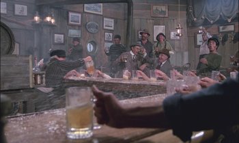 Movie still from “Pete's Dragon” (1977), directed by Don Chaffey – A group of people sitting at a bar drinking beer; Wide shot, Low angle